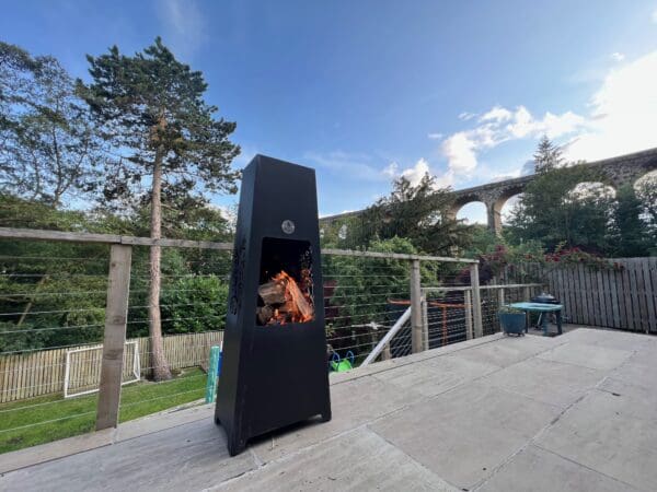 Luxury Chiminea with a raging fire and trees and viaduct in background